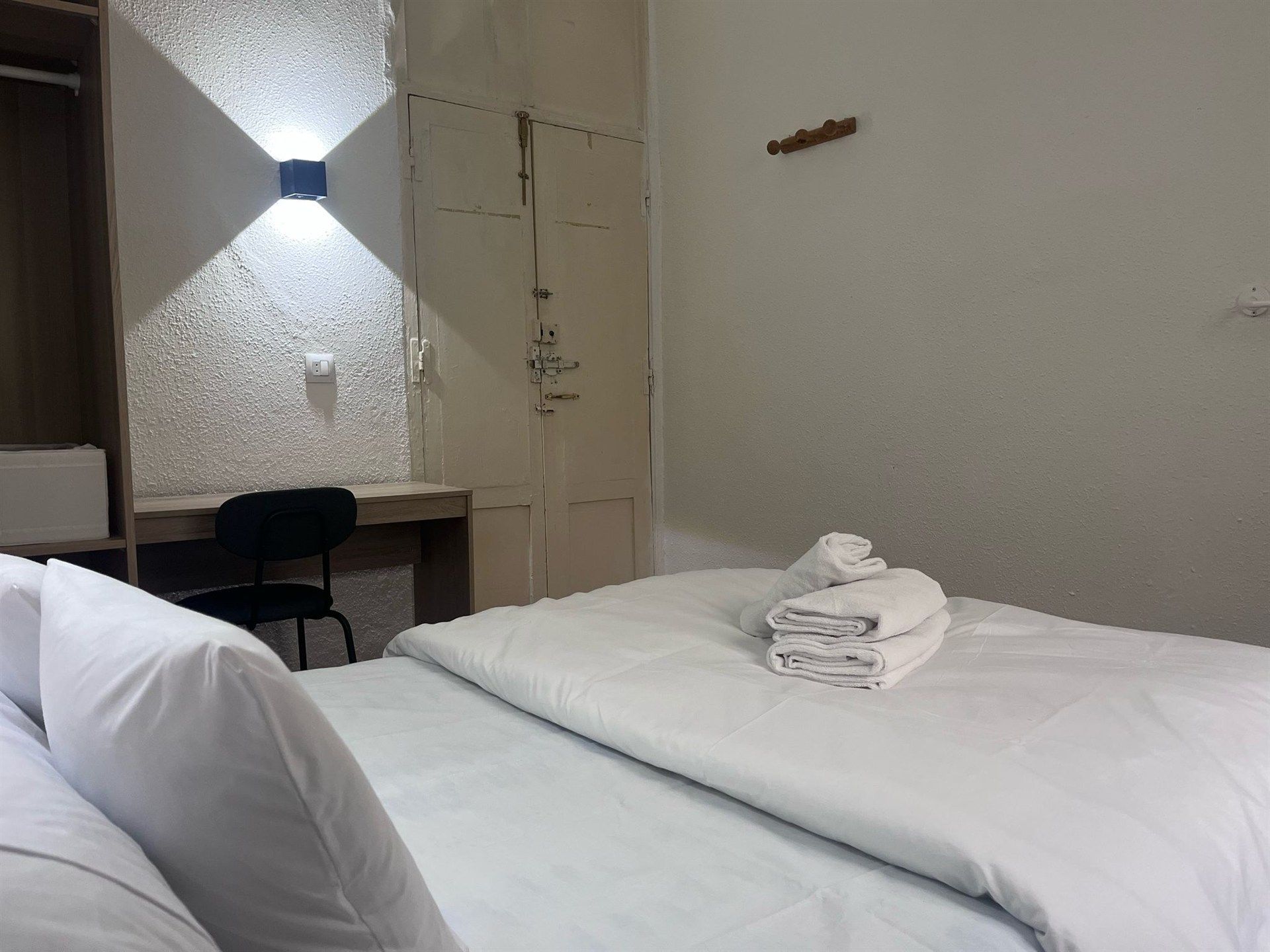 A hotel room with a bed , desk and chair.