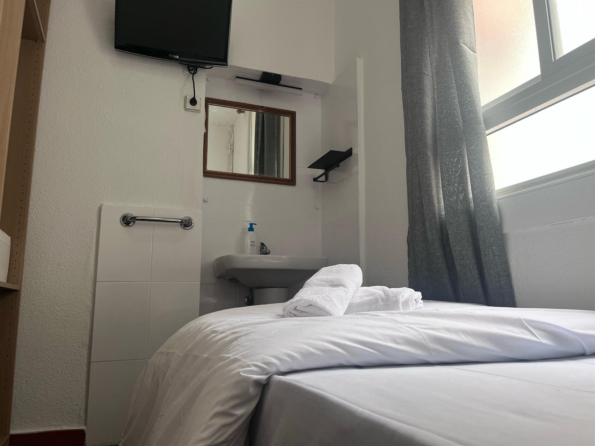 A bedroom with two beds , a television , a sink and a mirror.