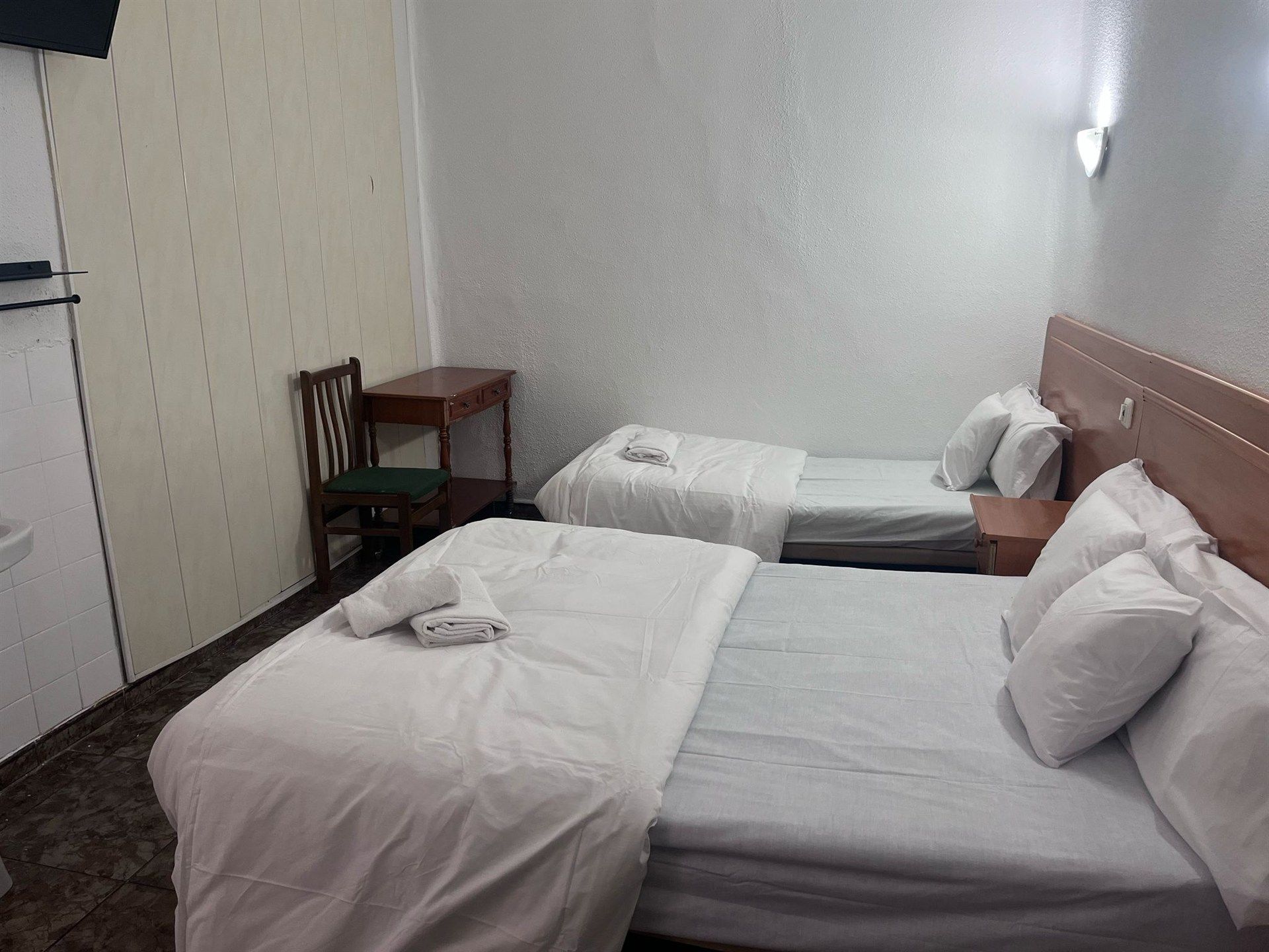A hotel room with two beds , a desk and a chair.