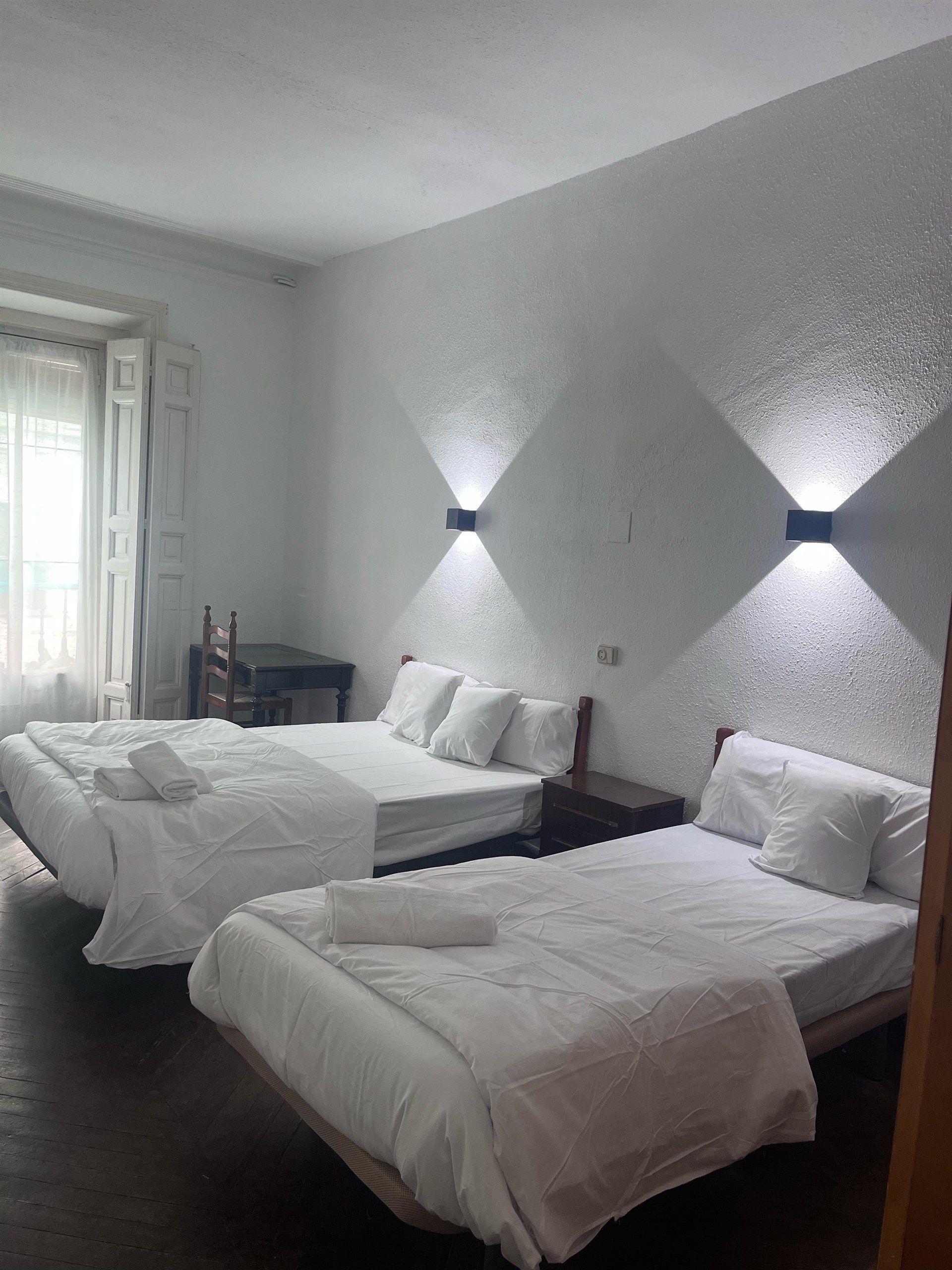 A hotel room with two beds and a window.