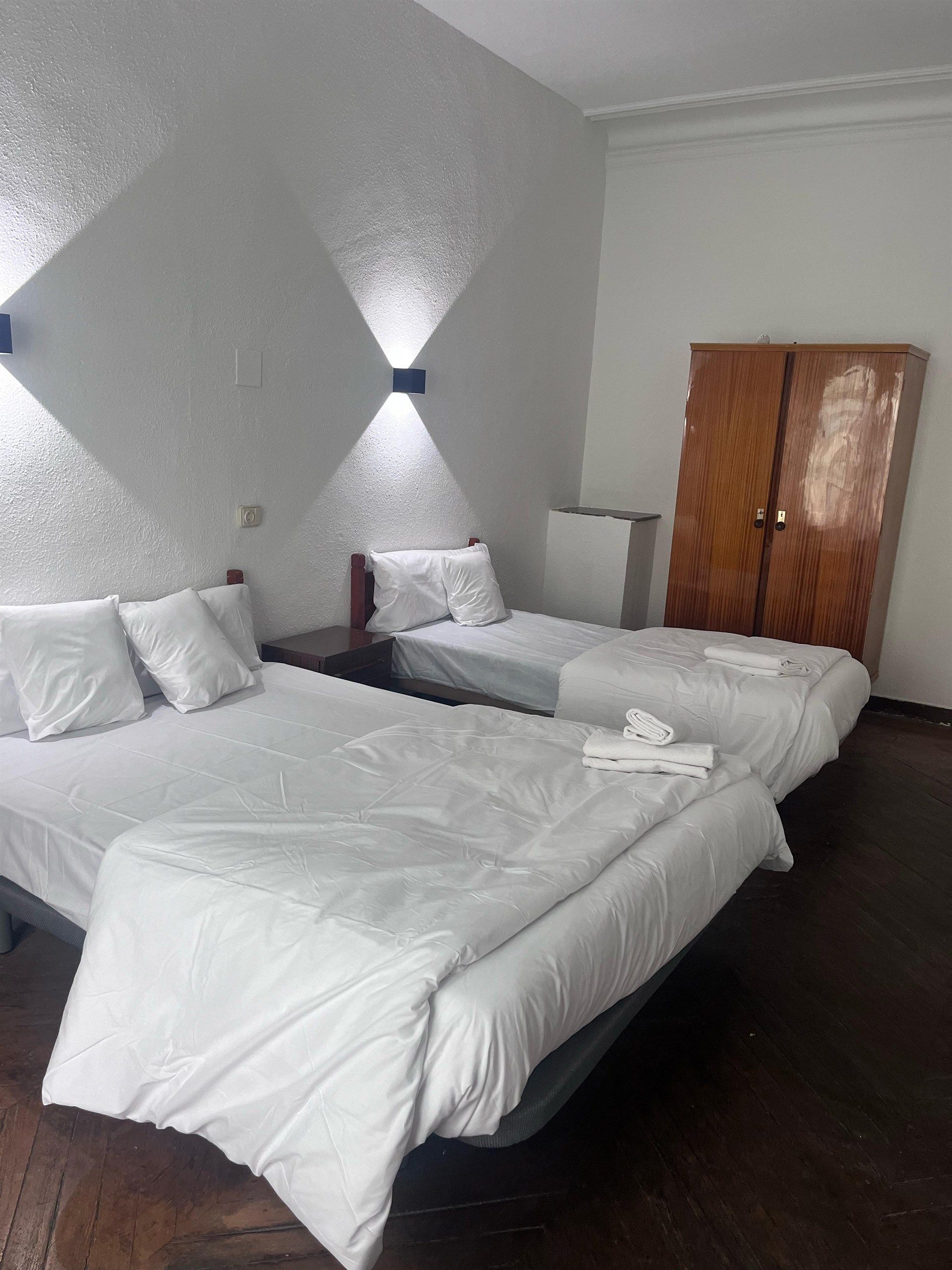A hotel room with two beds and a wardrobe.