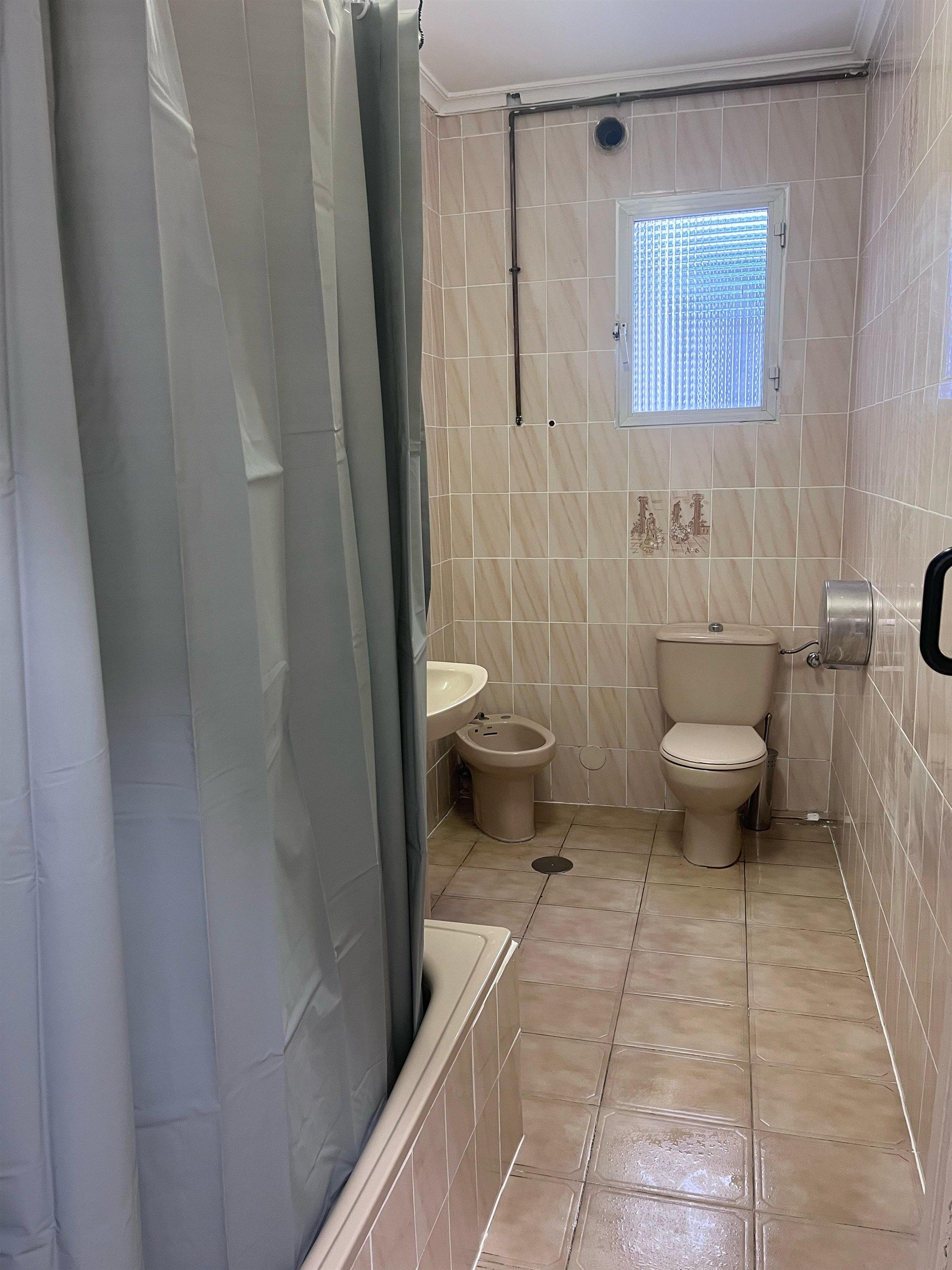A bathroom with a toilet , sink , and shower curtain.