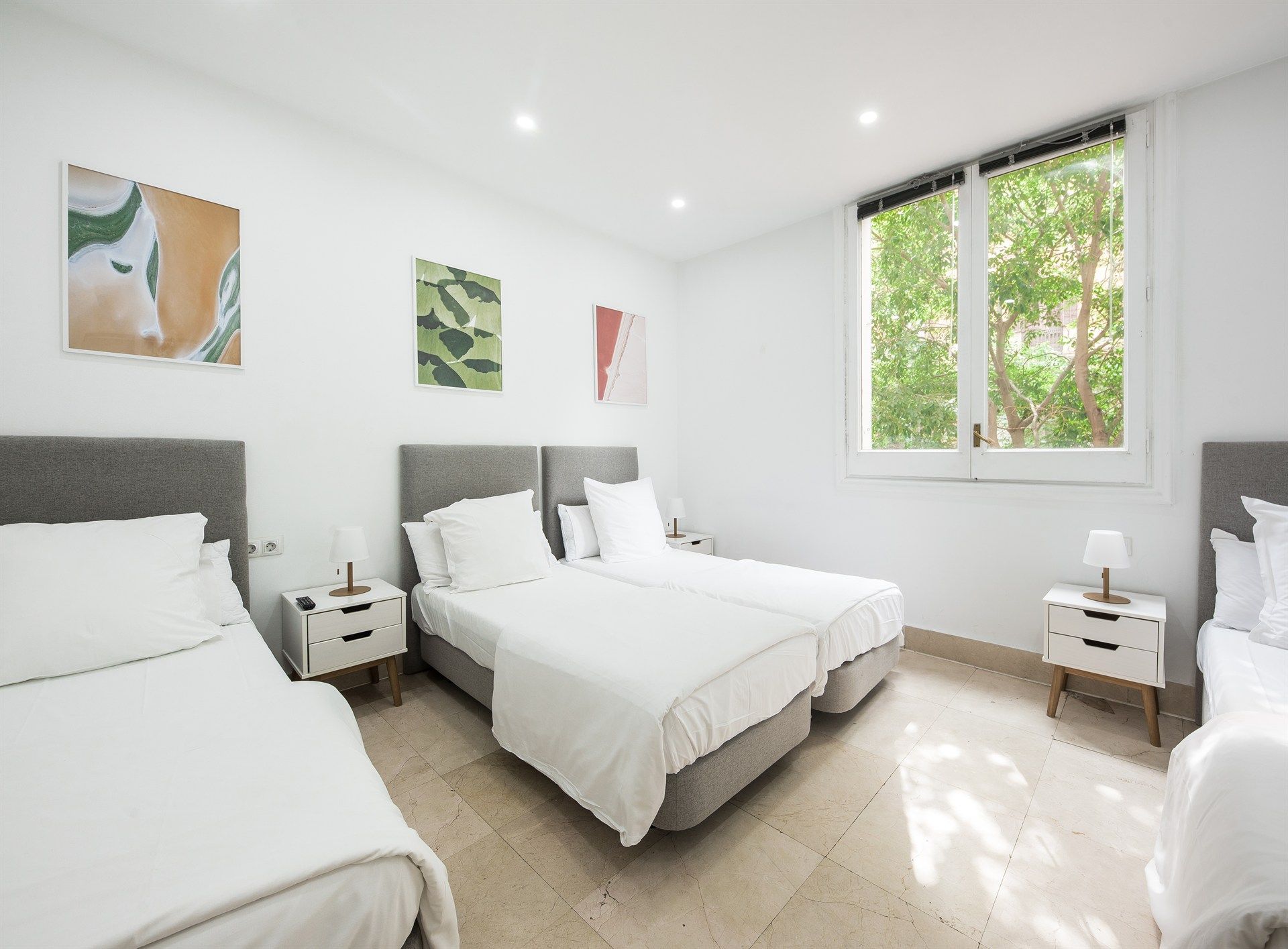 A bedroom with three beds and two nightstands.