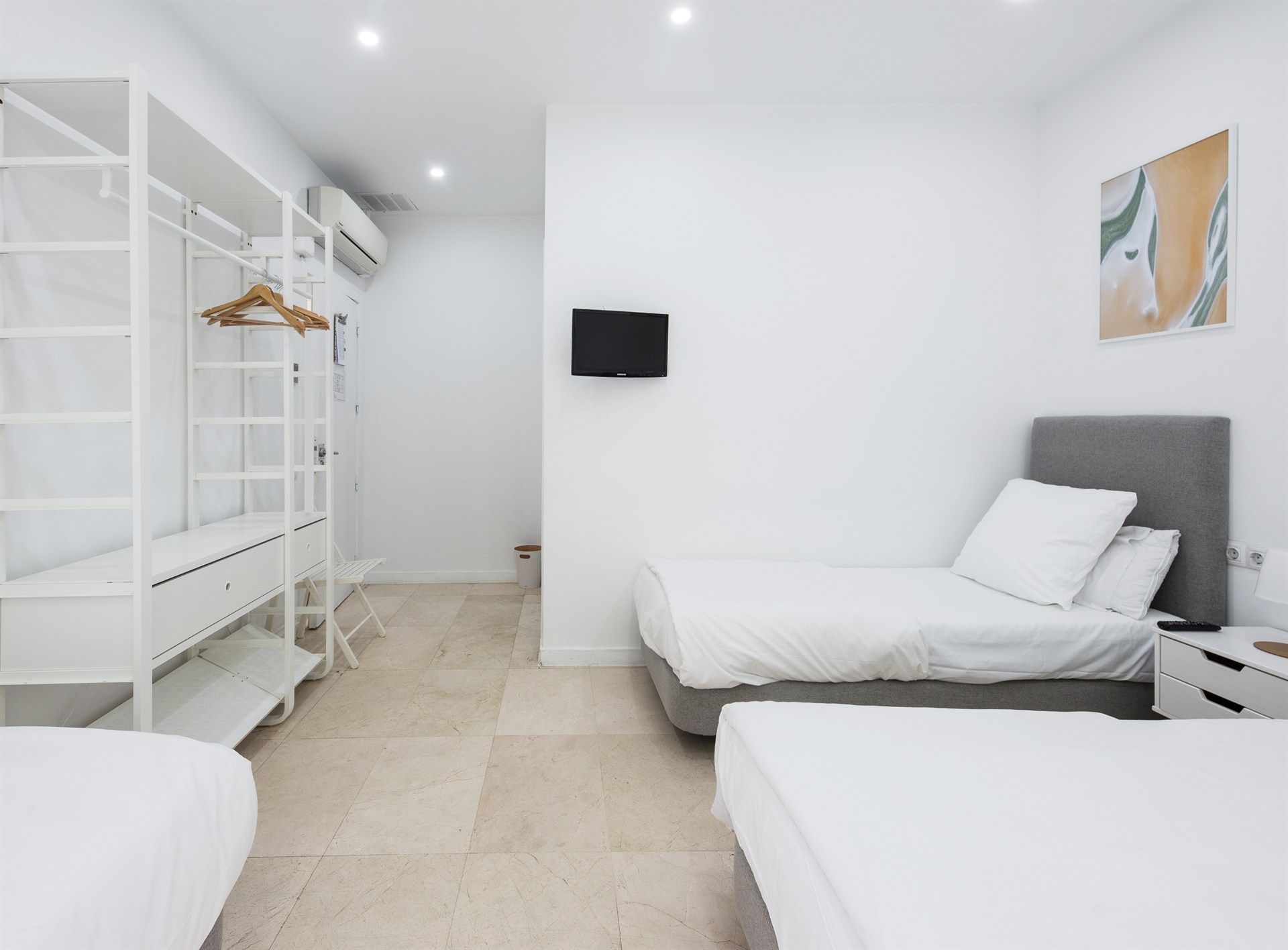 A bedroom with two beds and a television on the wall.