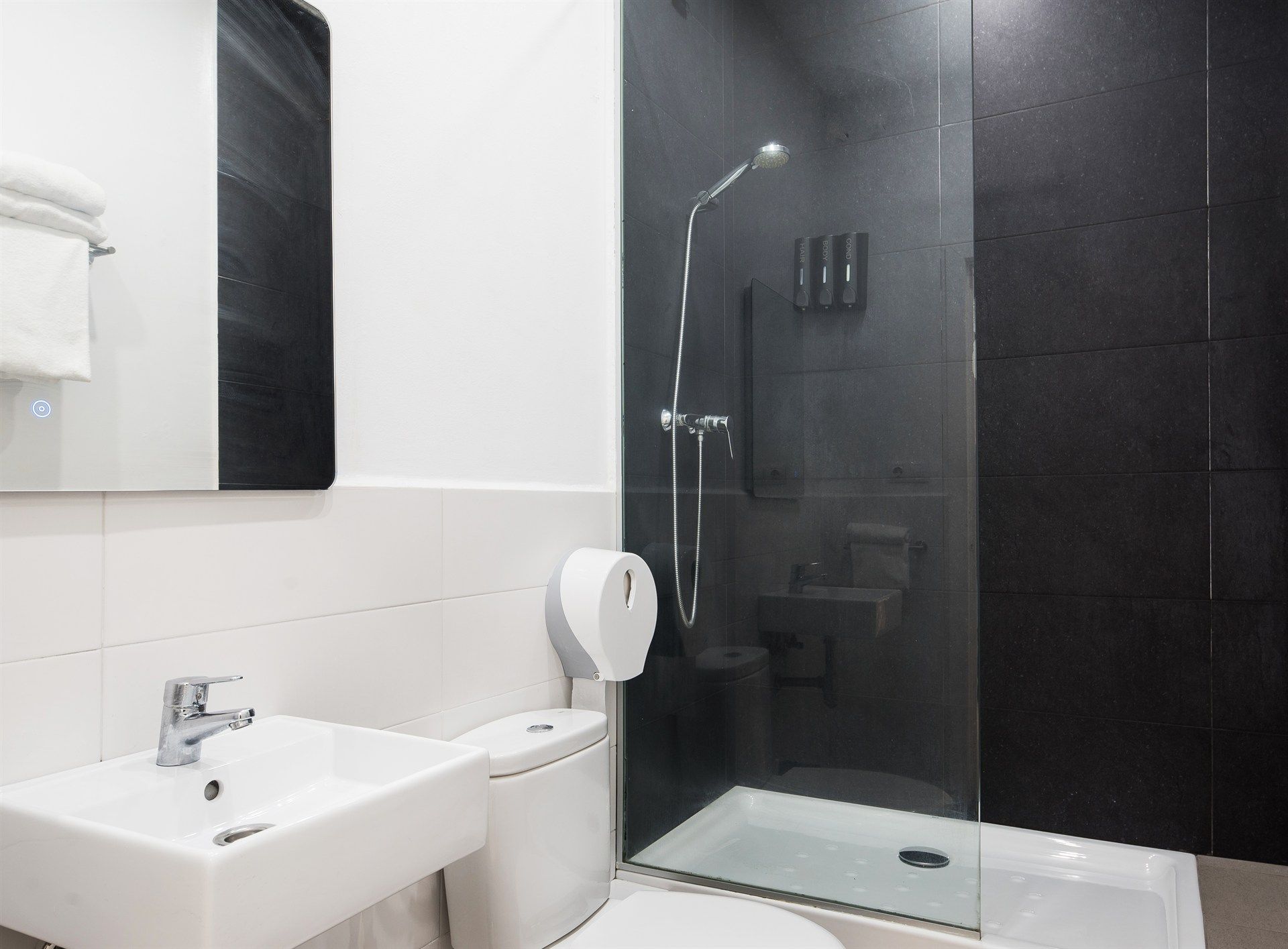 A bathroom with a toilet , sink and shower.