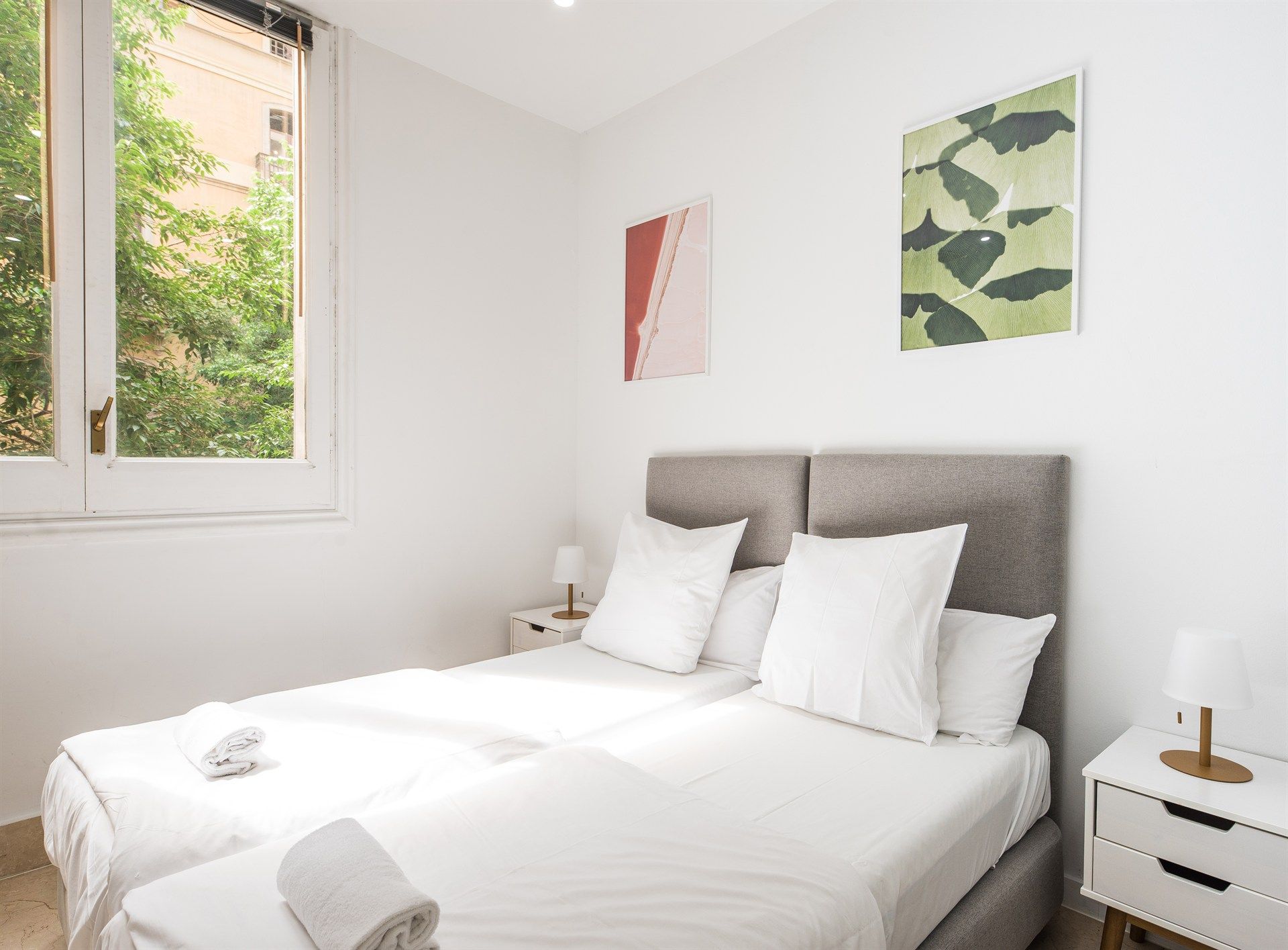 A bedroom with two beds , a nightstand and a window.