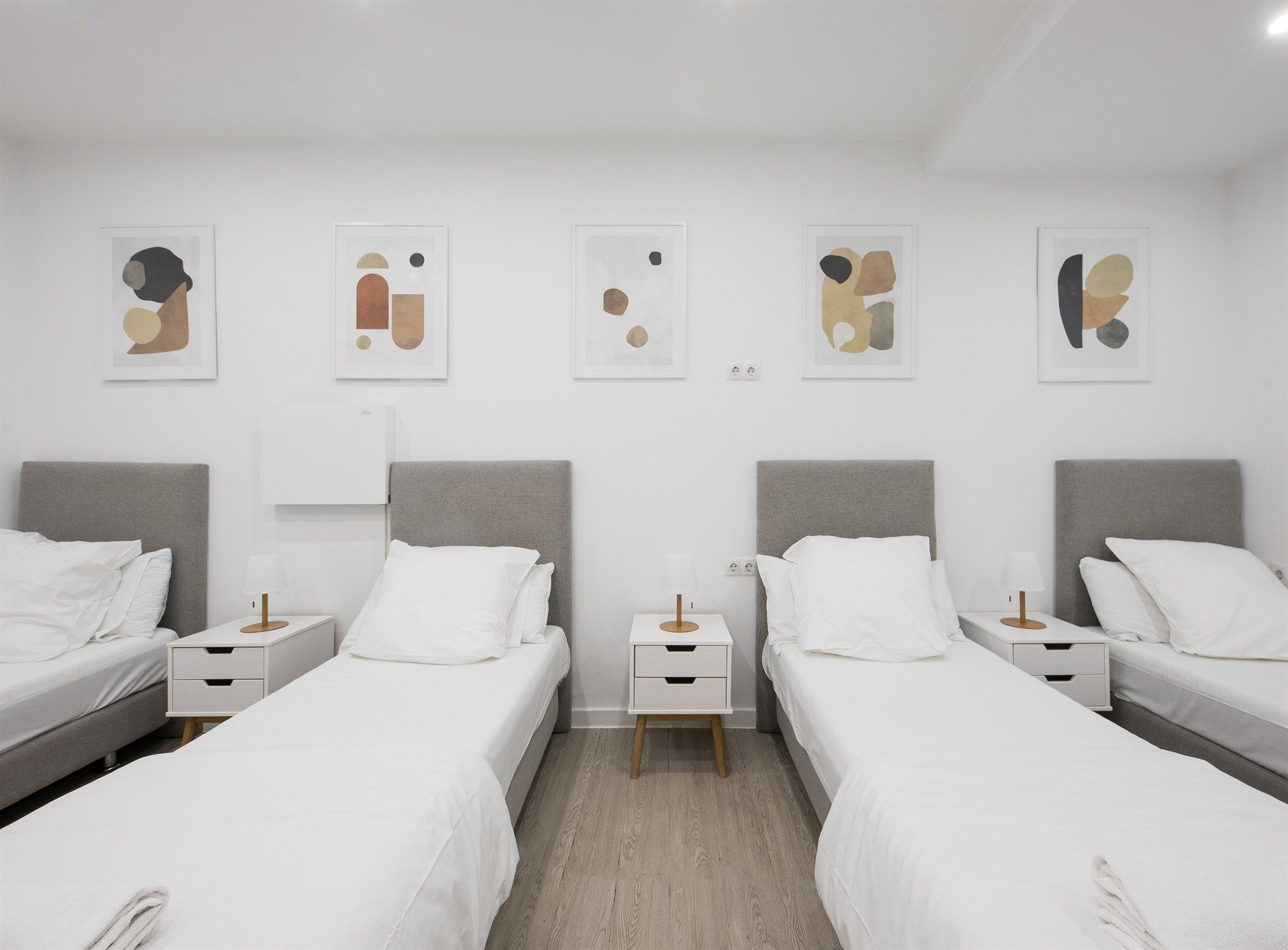 A bedroom with four beds and two nightstands.
