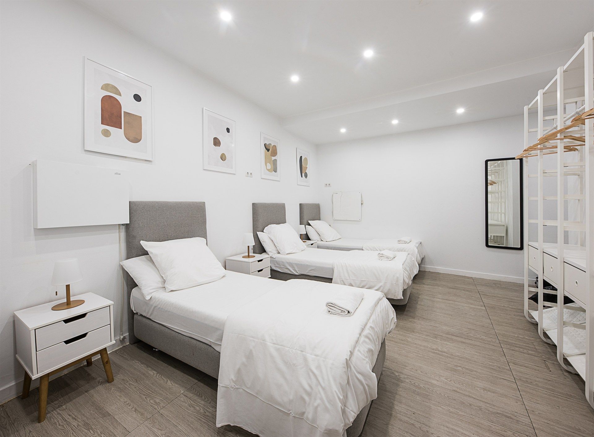 A bedroom with three beds , a nightstand , a mirror and a closet.