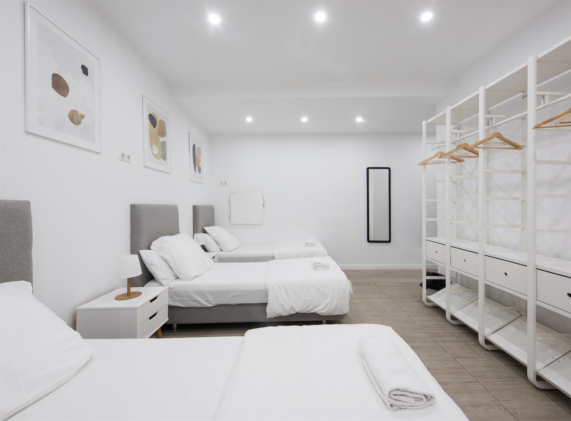 A bedroom with three beds , a nightstand , a mirror and a closet.