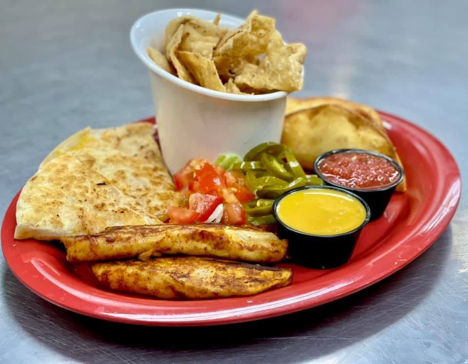Tray with two samosas, spiced rice, and brown chutney on a paper-lined plate.