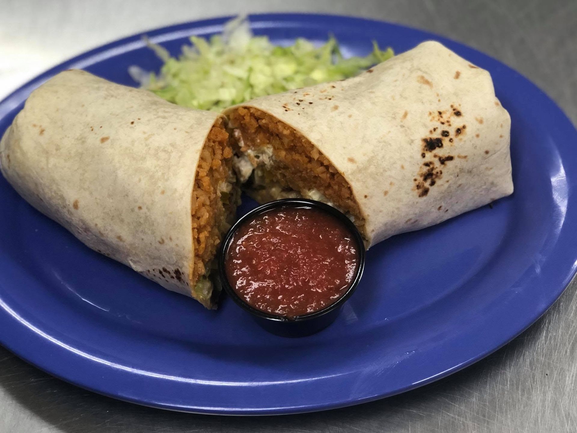 Stack of cabbage tacos on a plate with red sauce and shredded vegetables