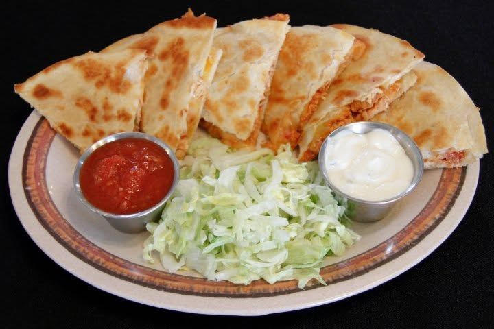 Plate of quesadillas with salsa, sour cream, and shredded lettuce on a platter
