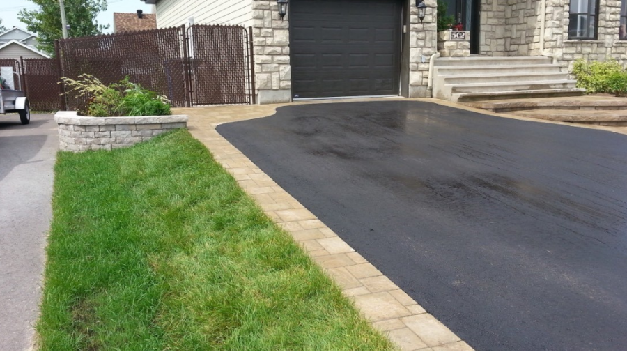 Une allée menant à une maison avec une porte de garage noire