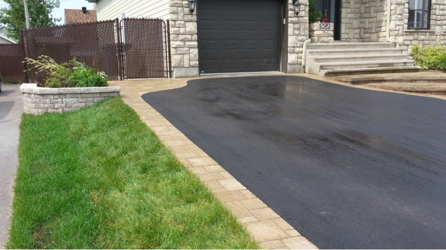 Une allée menant à une maison avec une porte de garage noire
