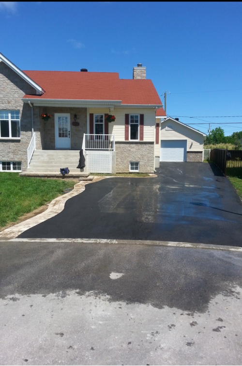 Une maison avec un toit rouge et une allée noire
