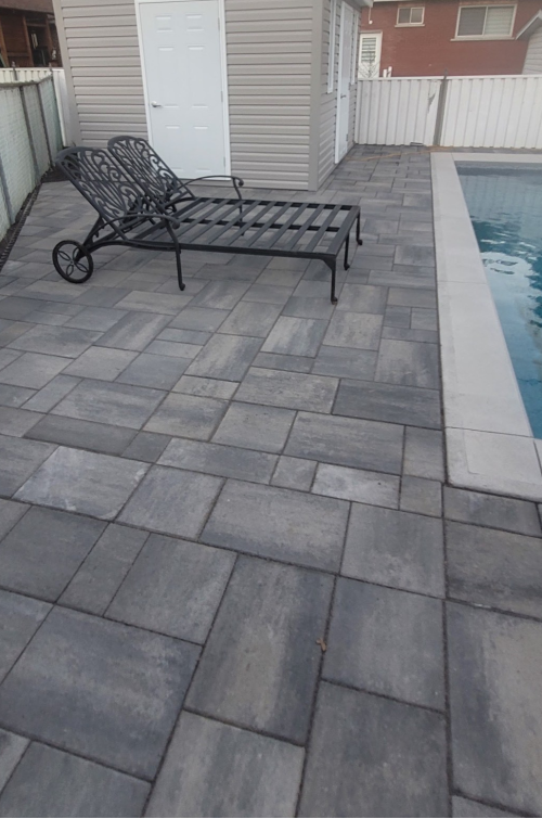 Une chaise longue est assise sur une terrasse à côté d'une piscine.