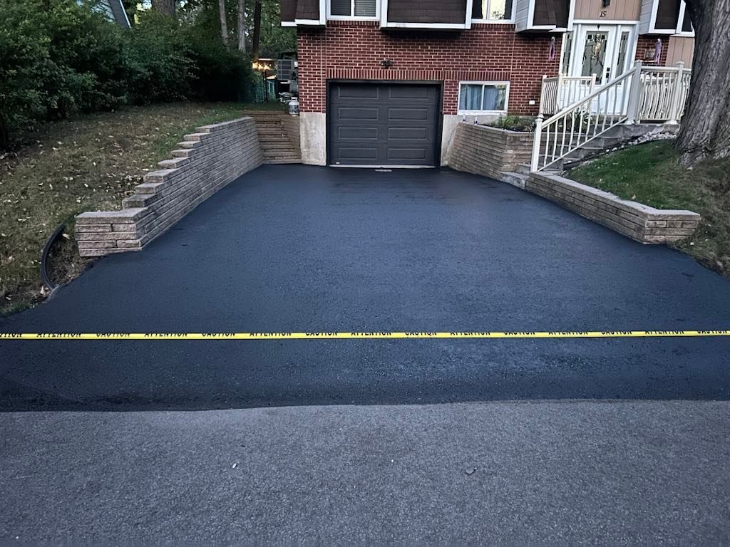 Une allée noire menant à une maison en briques avec une porte de garage.