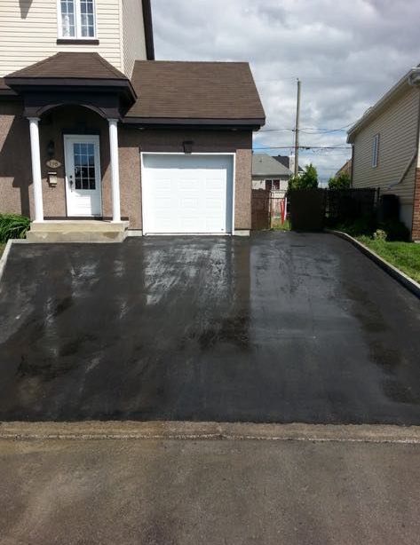 Une allée menant à une maison avec une porte de garage blanche