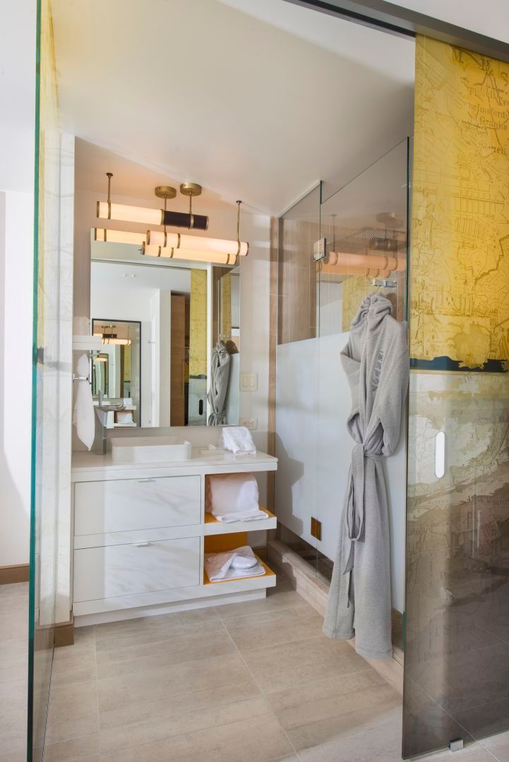 Modern bathroom with marble vanity, glass shower, and gold accents.