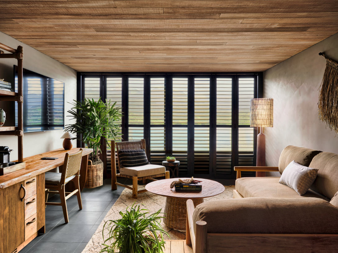 Cozy living room with wood ceiling, large window, sofa, and desk.
