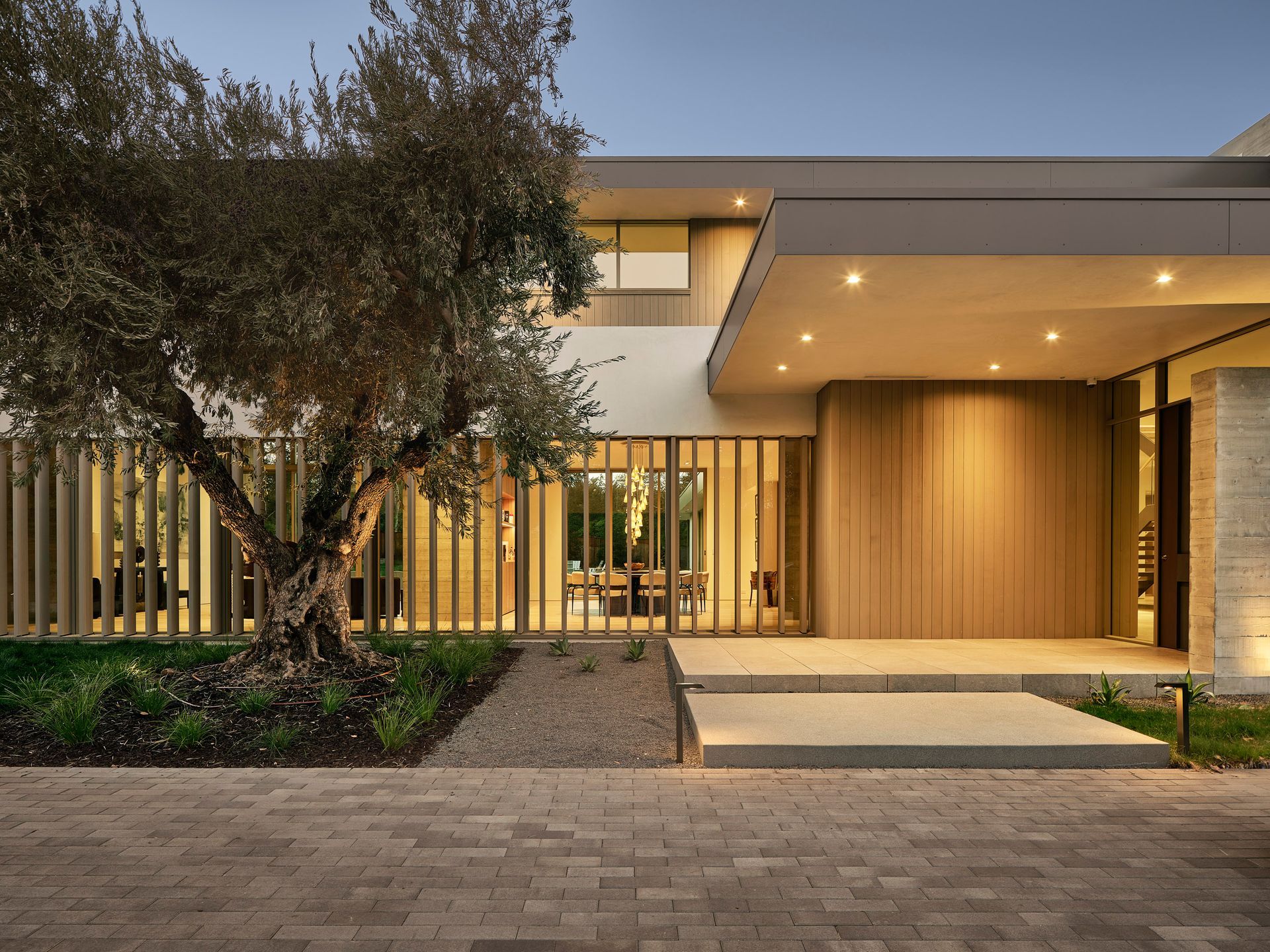 Modern home exterior with wooden accents and mature tree.