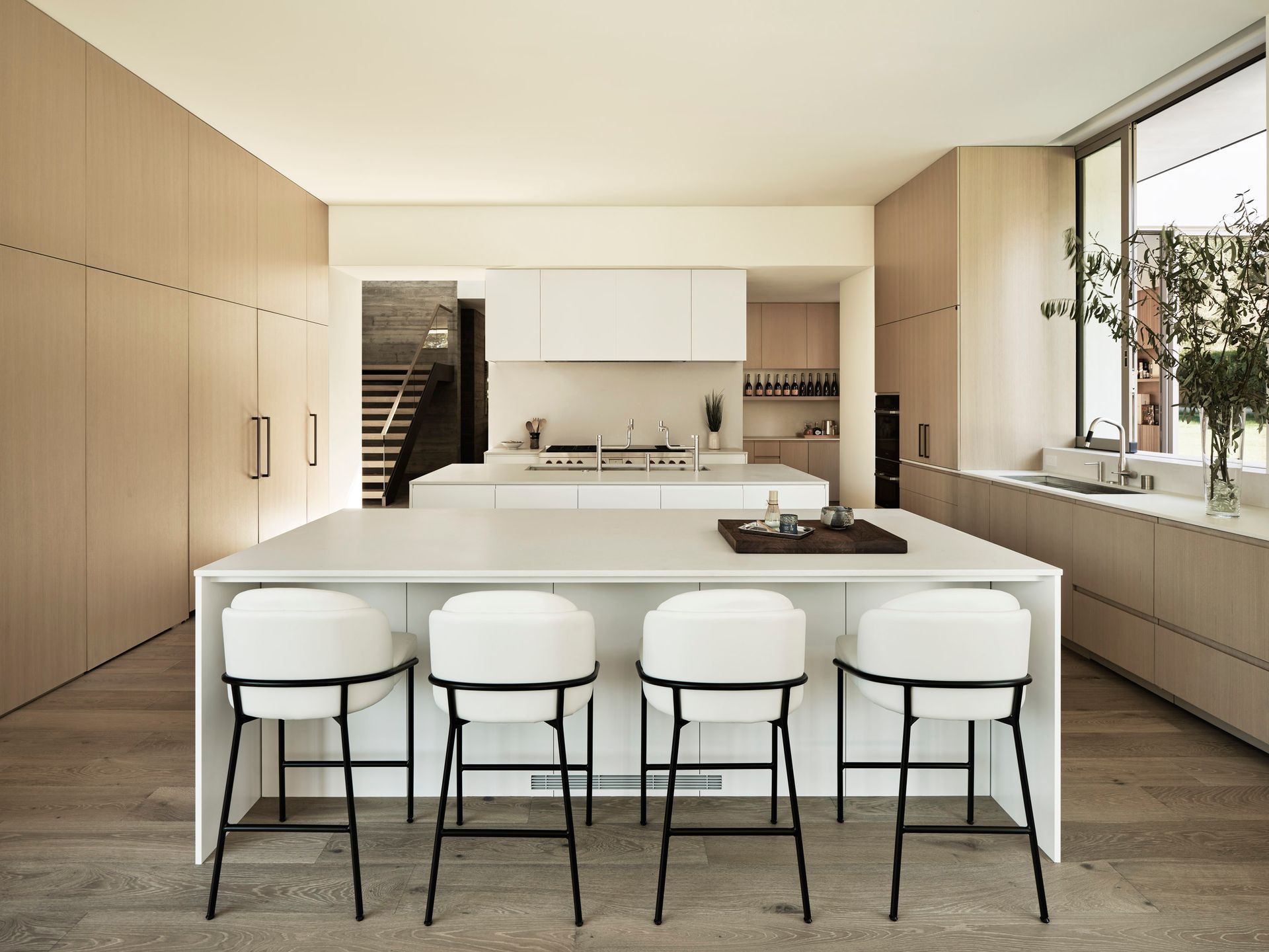 Modern kitchen with white island, four bar stools, and light wood cabinetry.