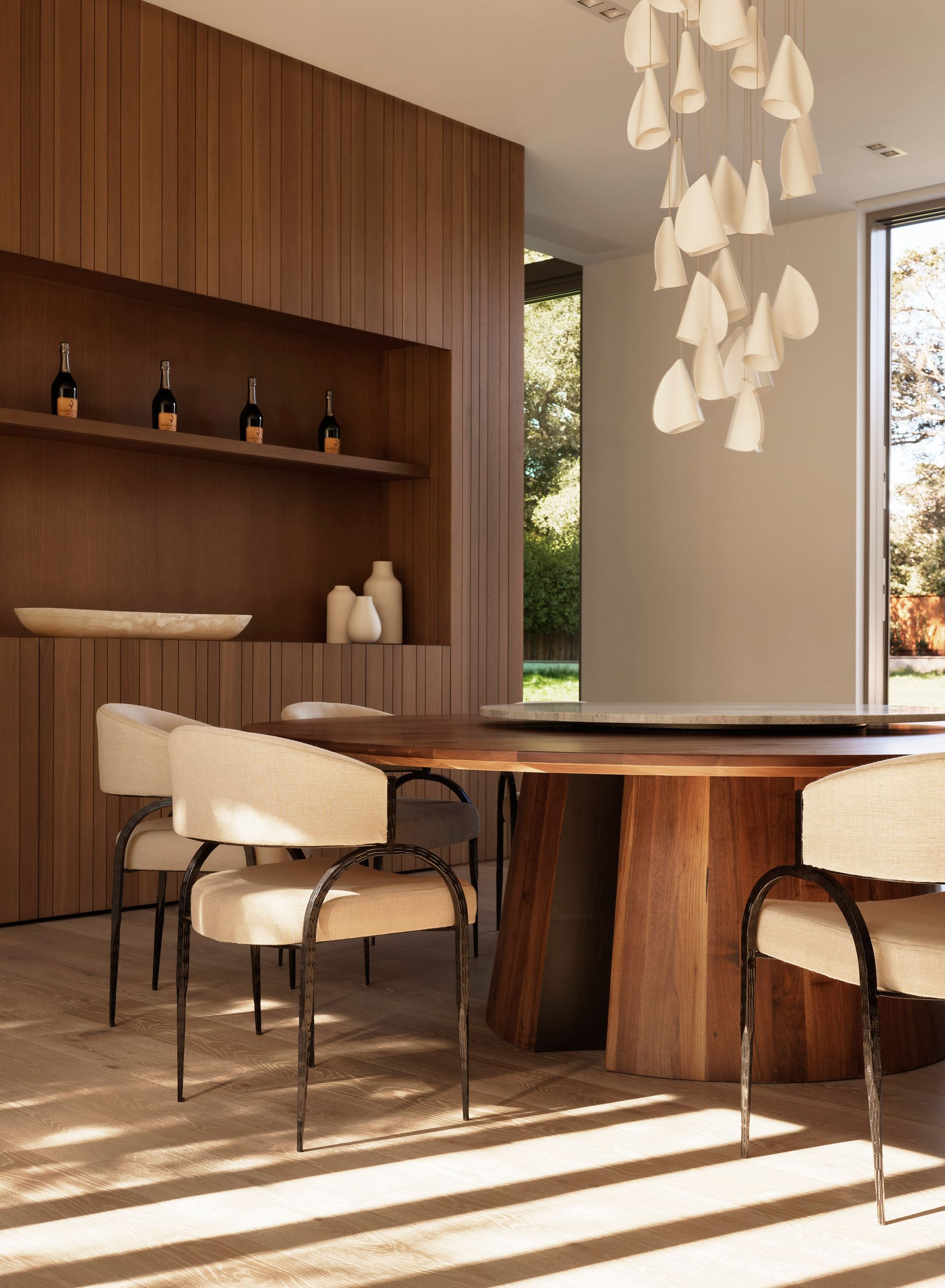 Dining room with wooden table and chairs, built-in wooden shelving, and chandelier.