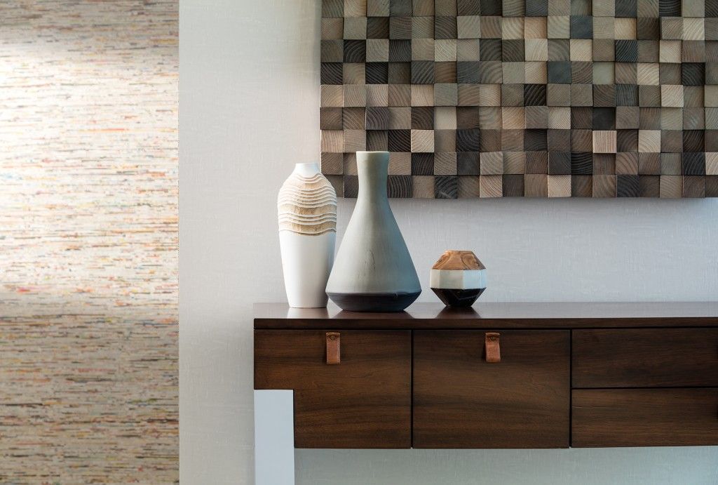 Wooden console table with vases and artwork on a white wall; natural light.