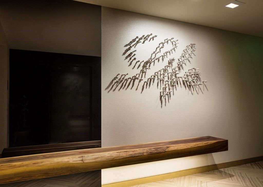 Wooden bench beneath wall art, near a doorway.