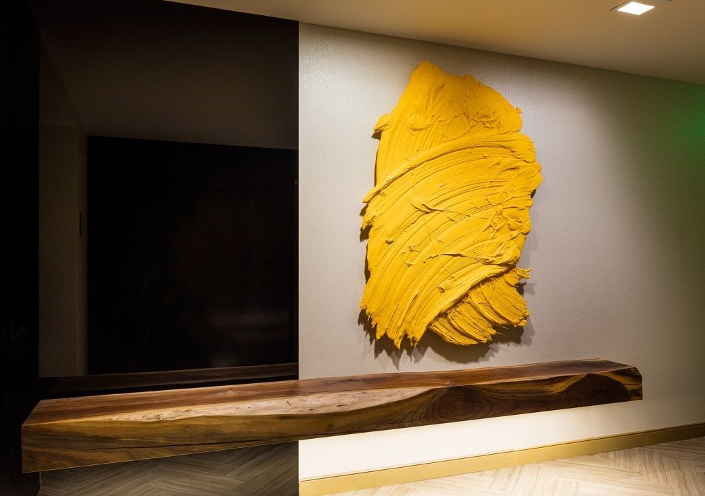 Yellow abstract art on gray wall, above wooden shelf. Dark doorway visible.
