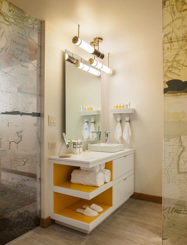Modern white bathroom vanity with yellow accents, a mirror, and overhead lights.