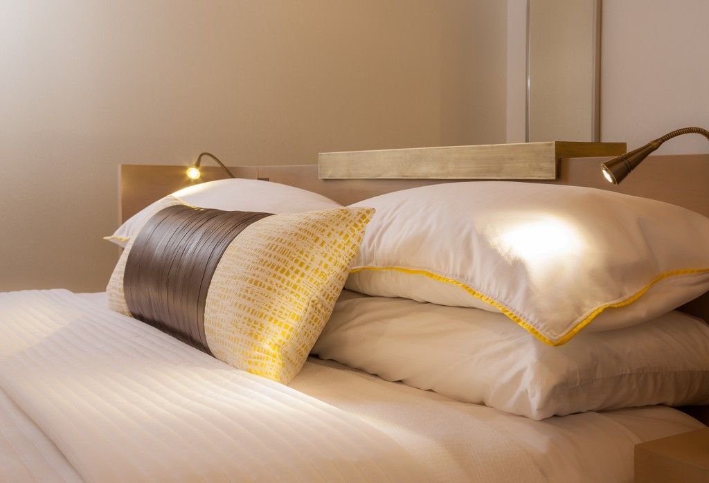 Bed with white pillows and a decorative brown and yellow pillow.