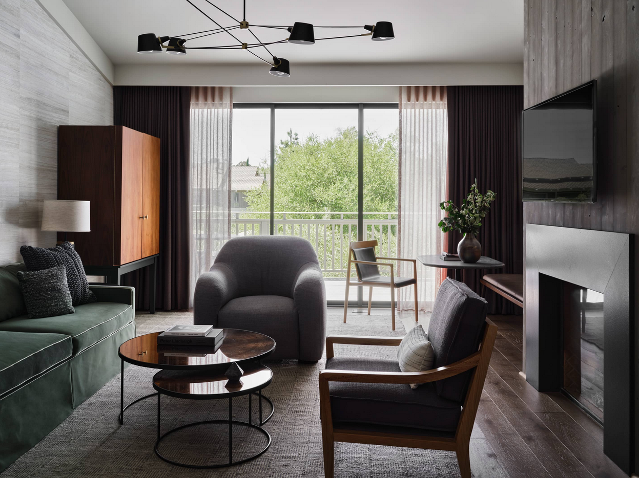 Living room with green sofa, gray armchair, window, and modern fireplace.
