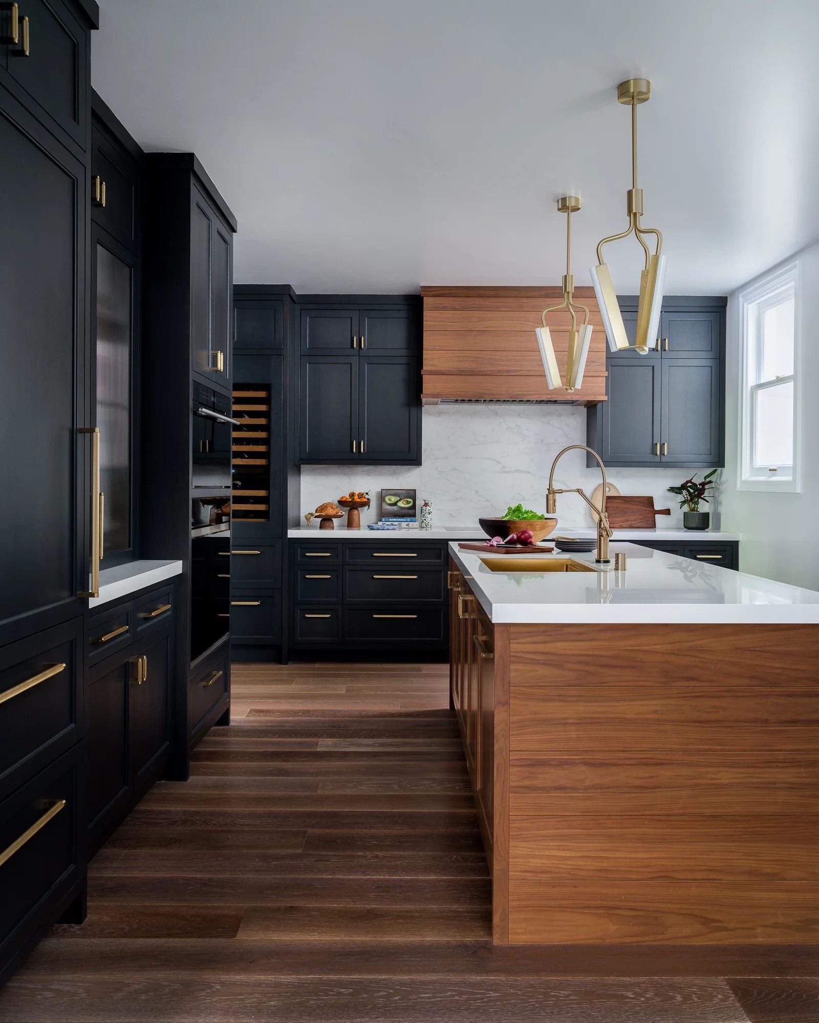 Modern kitchen with dark blue cabinets, wooden island, and gold accents.