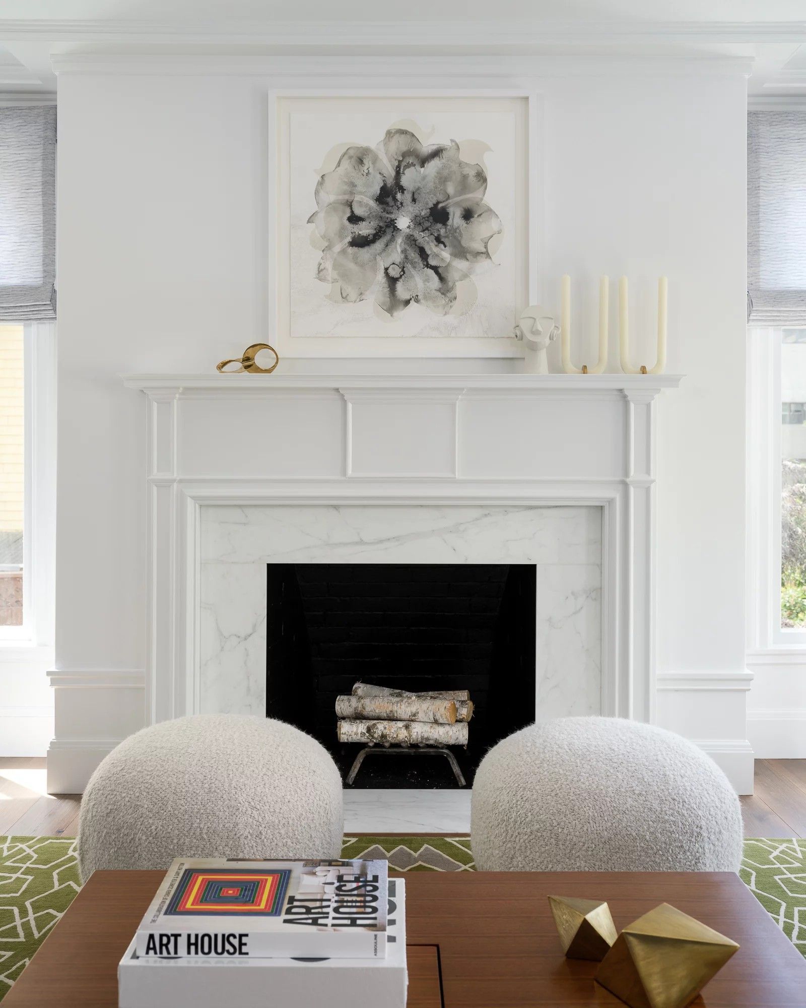 White fireplace with abstract art and fluffy poufs.