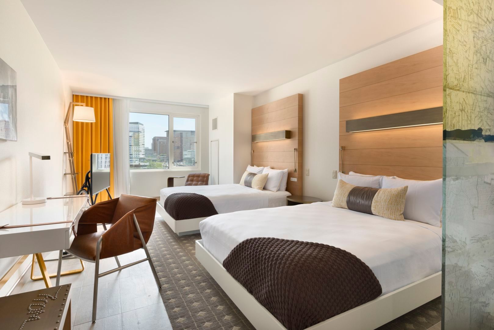 Hotel room with two beds, white bedding, brown accents, and city view.