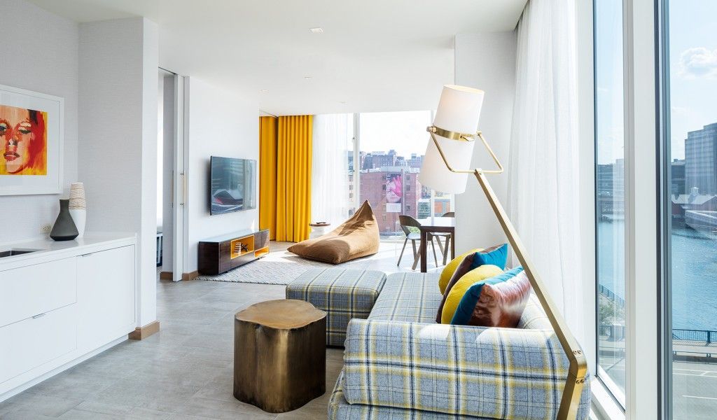 Bright living room with city view, plaid sofa, floor lamp, yellow curtains.