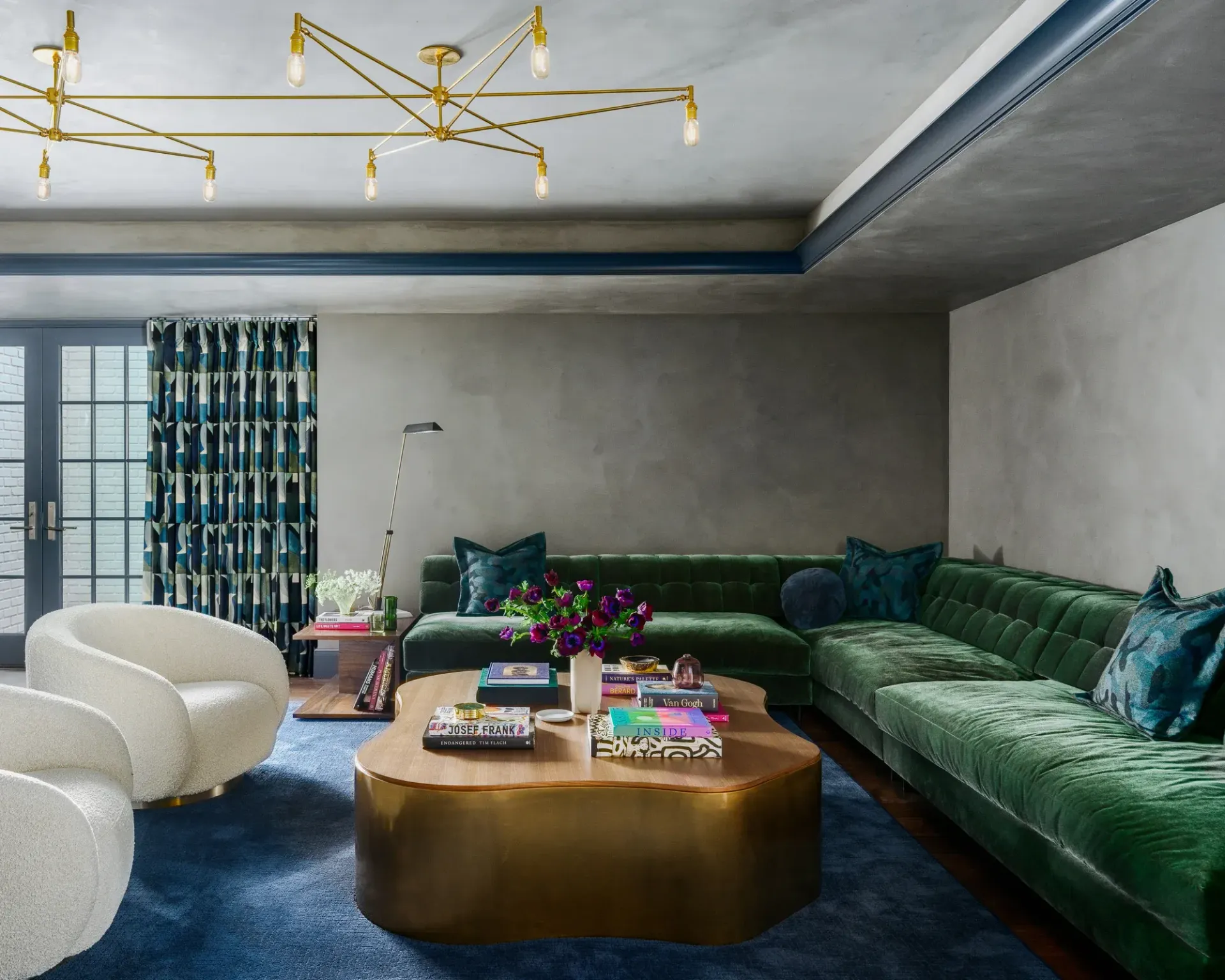 Green velvet sofa in a living room, with gold coffee table and white chairs.