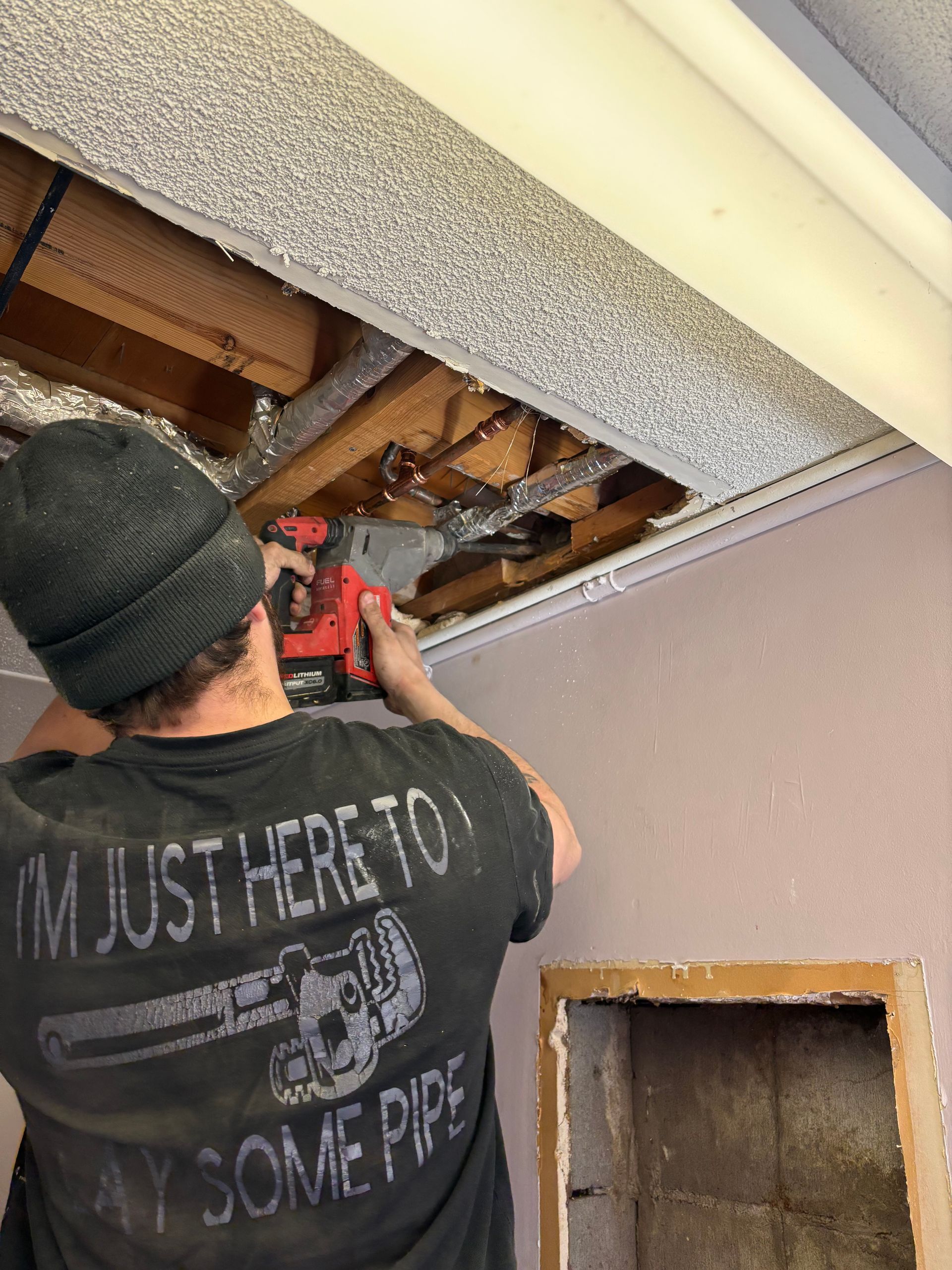 Person using a power tool on ceiling, working in a confined space.