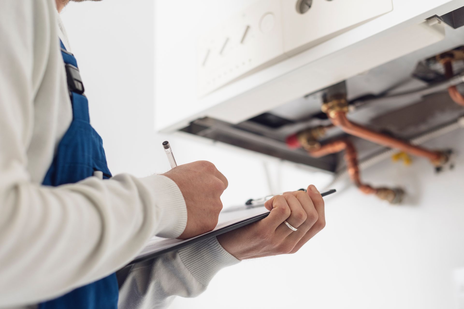 Heating installation contractor checking copper pipes and documenting a home boiler service.