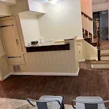 Empty lobby with beige walls, dark wood trim, stairs, and a doorway in the background.