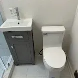 Small bathroom with a white toilet beside a gray vanity and sink