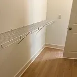 Empty hallway with a white wire shelf installed along the wall near a doorway.