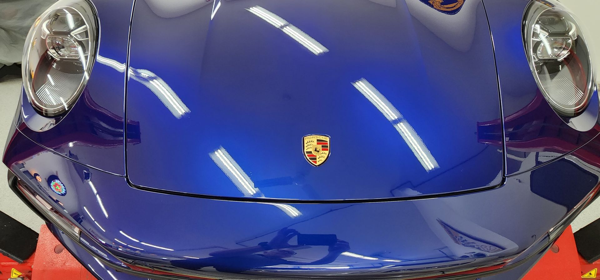 Close-up of a blue Porsche sports car hood with the Porsche emblem in the center.