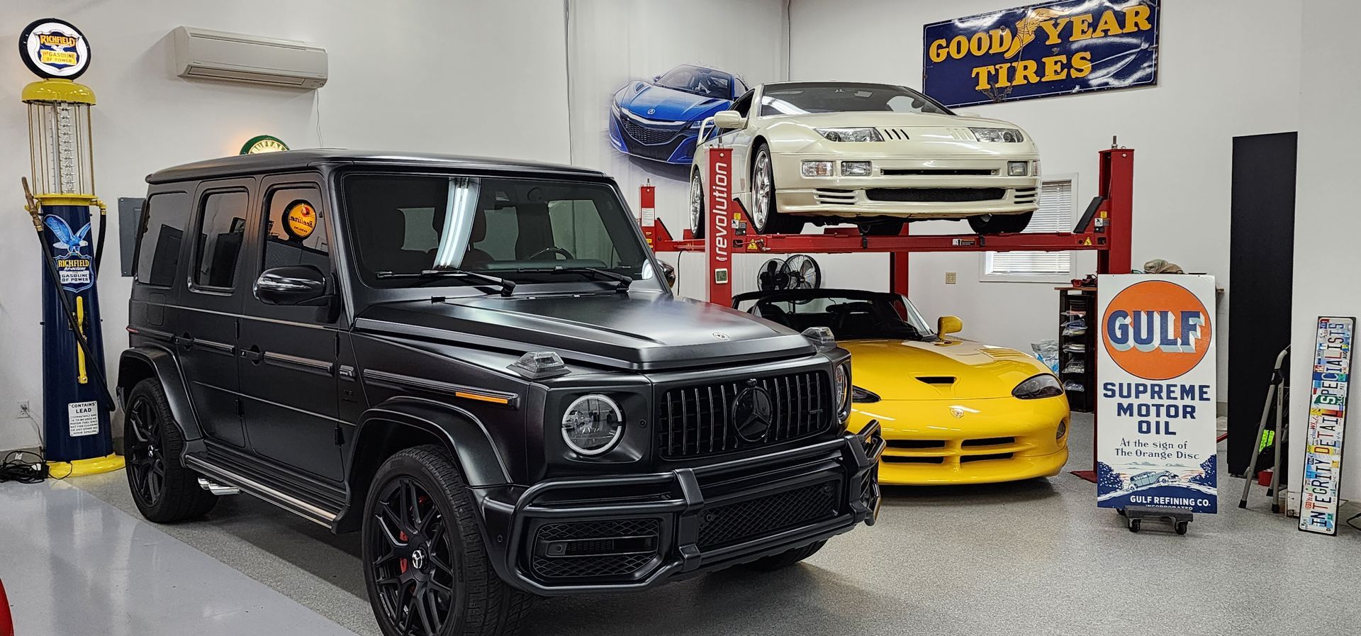 Black SUV parked in a garage with a vintage gas pump and other classic cars.