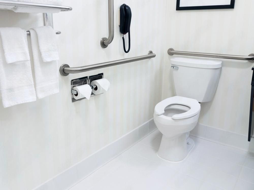 a bathroom with a toilet , handrails , and towels .