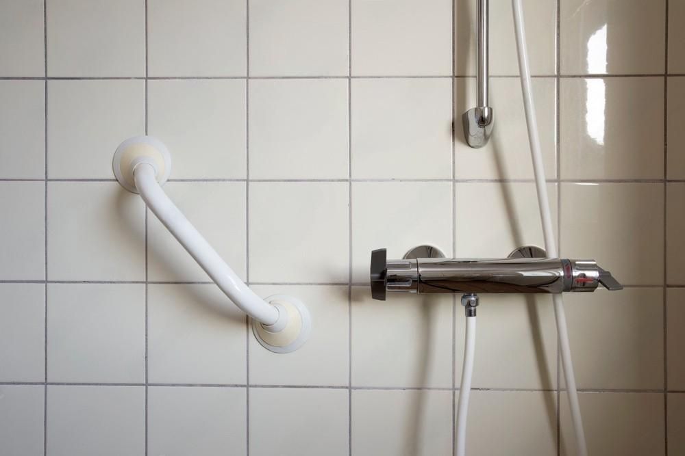 a shower with a hand rail and a shower head .