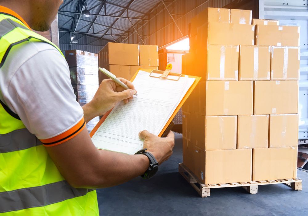 A Man Is Writing On A Clipboard In A Warehouse — James Fast Freight in Wagga Wagga, NSW
