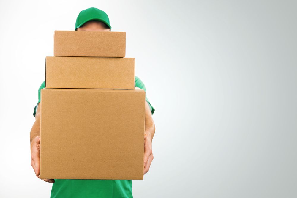 A Delivery Man Is Holding A Stack Of Cardboard Boxes — James Fast Freight in Wagga Wagga, NSW