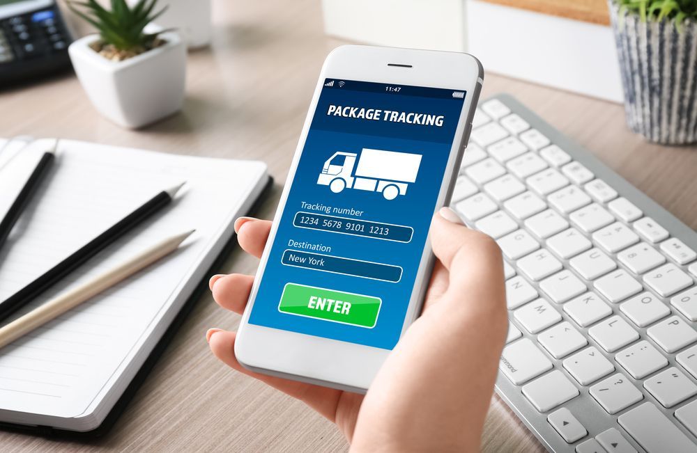 A Person Is Holding A Cell Phone In Front Of A Keyboard — James Fast Freight in Wagga Wagga, NSW